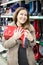 Woman with red waterproof shoes in hands buying in shop