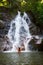 Woman refreshing herself in beautiful waterfall