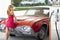 Woman refuel the car. Gas station. Girl against red retro automobile.