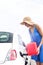 Woman refueling car against clear sky on sunny day