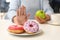 Woman refusing to eat donuts and choosing apple instead. Diabetes concept