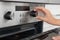 Woman regulating cooking mode on oven panel