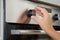 Woman regulating cooking mode on oven panel