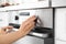 Woman regulating cooking mode on oven panel in kitchen