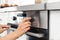 Woman regulating cooking mode on oven panel in kitchen