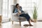 Woman relax on armchair in living room with laptop