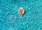 Woman relaxes on a donut shaped float over blue, sparkling pool water