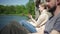 Woman relaxes by the lake with phone and man. Spbd two people couple sit on pier and have a rest