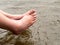 Woman relaxes by the river sitting, swing her feet to the water surface.