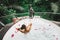 Woman relaxing bath tub full of foam outdoors with jungle view. View from behind