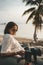 Woman relaxing on beanbag at the beach and making timelapse video with her camera on tripod