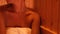 Woman relaxing on bench in wooden sauna room in beauty spa. Relaxing woman enjoying bath room in spa resort. Body and