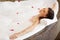 Woman Relaxing in Bubble Bath With Rose Petals. Body Care