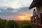 Woman relaxing in the countryside, sitting in balcony wooden cabin, watching dramatic sky at sunset, traveling wanderlust,