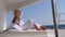 woman relaxing on a cruise catamaran sail boat wearing white summer dress