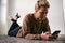 Woman Relaxing At Home Looking At Social Media And Text Messages On Mobile Phone Lying On Carpet