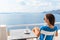 Woman relaxing on hotel balcony enjoying sea view drinking coffee cup during morning breakfast. Luxury resort travel