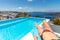 Woman relaxing by infinity pool in Greece, Santorini. Sea view with Fira town overlooking. Travel lifestyle background