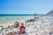 Woman relaxing on italian beach. Uneven Conero coast line, pebble beach, turquoise water real people, rear view, sunny day,