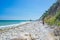 Woman relaxing on italian beach. Uneven Conero coast line, pebble beach, turquoise water real people, rear view, sunny day,