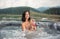 Woman relaxing in the Jacuzzi in the water and drinking cocktail against background of river, forest and hills