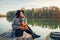 Woman relaxing on lake pier by boat admiring autumn landscape holding branches with leaves. Fall season activities