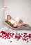 Woman relaxing in salt room with book, roses and petals