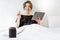 Woman relaxing with a smart speaker and tablet in the bedroom