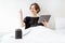 Woman relaxing with a smart speaker and tablet in the bedroom