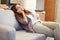 Woman Relaxing On Sofa Talking On Phone In New Home