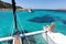 Woman relaxing on a summer sailing cruise, sitting on a luxury catamaran near picture perfect white sandy beach on