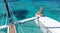 Woman relaxing on a summer sailing cruise, sitting on a luxury catamaran in picture perfect turquoise blue lagoon near