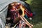 Woman relaxing in tent at camping during summer vacation. Female waving to her friends