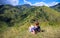 Woman relaxing on the top of hill on natural mountain background. Tourist travels through the mountains