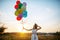 Woman releases balloons into the sky at sunset