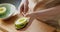 Woman removing avocado half with spoon at kitchen