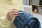 Woman removing chewing gum from jeans indoors, closeup