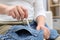 Woman removing chewing gum from jeans on sofa indoors, closeup