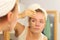 Woman removing facial clay mud mask in bathroom