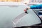 Woman removing ice from car windshield with glass scraper.