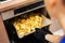 Woman removing prepared potatoes tray out of oven