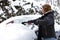 Woman removing snow from her car