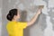 A woman repairman puts wallpaper glue on the wall. The wallpaper in the house and repair with their own hands yourself