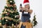 Woman repairman in santa hat holding electric drill near christmas tree