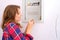 A woman repairs the electrical panel of the house