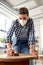 woman in respirator sanding old table with sponge