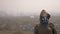 A woman in a respirator stands on the background of smoking factory pipes