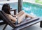 Woman resting on deckchair in swimming pool