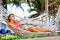 Woman is resting in the hammock under the palms on the tropical