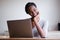 Woman resting head on hand sitting at desk with laptop